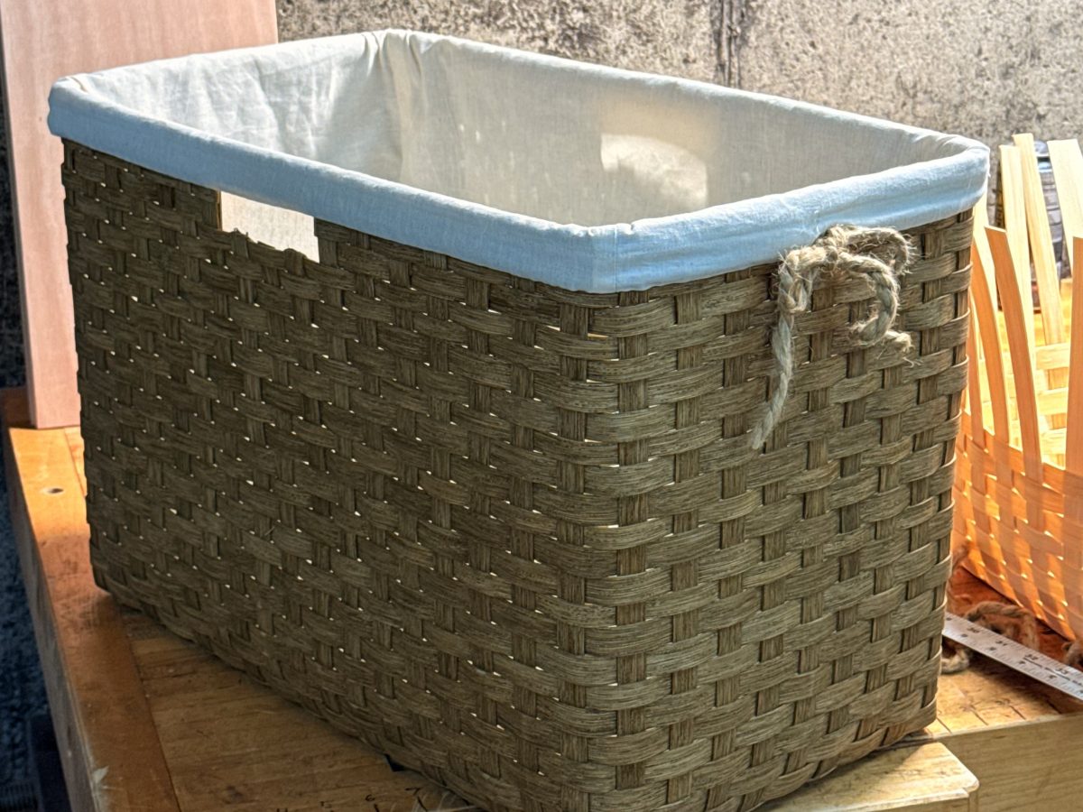 A handwoven storage basket with a cream fabric liner, on the bench in the shop
