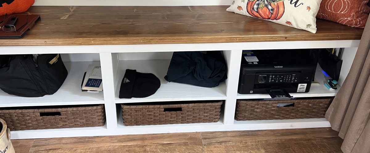 Three handwoven storage baskets along the bottom of a mudroom bench, under its cubbies
