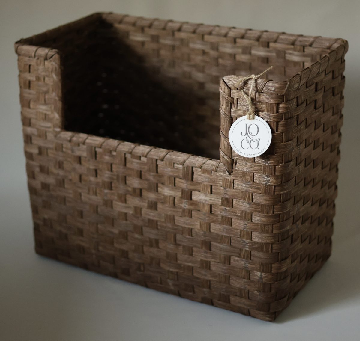 A handwoven basket cut away at one corner to sit around a vanity pipe, tagged Jo & Co.