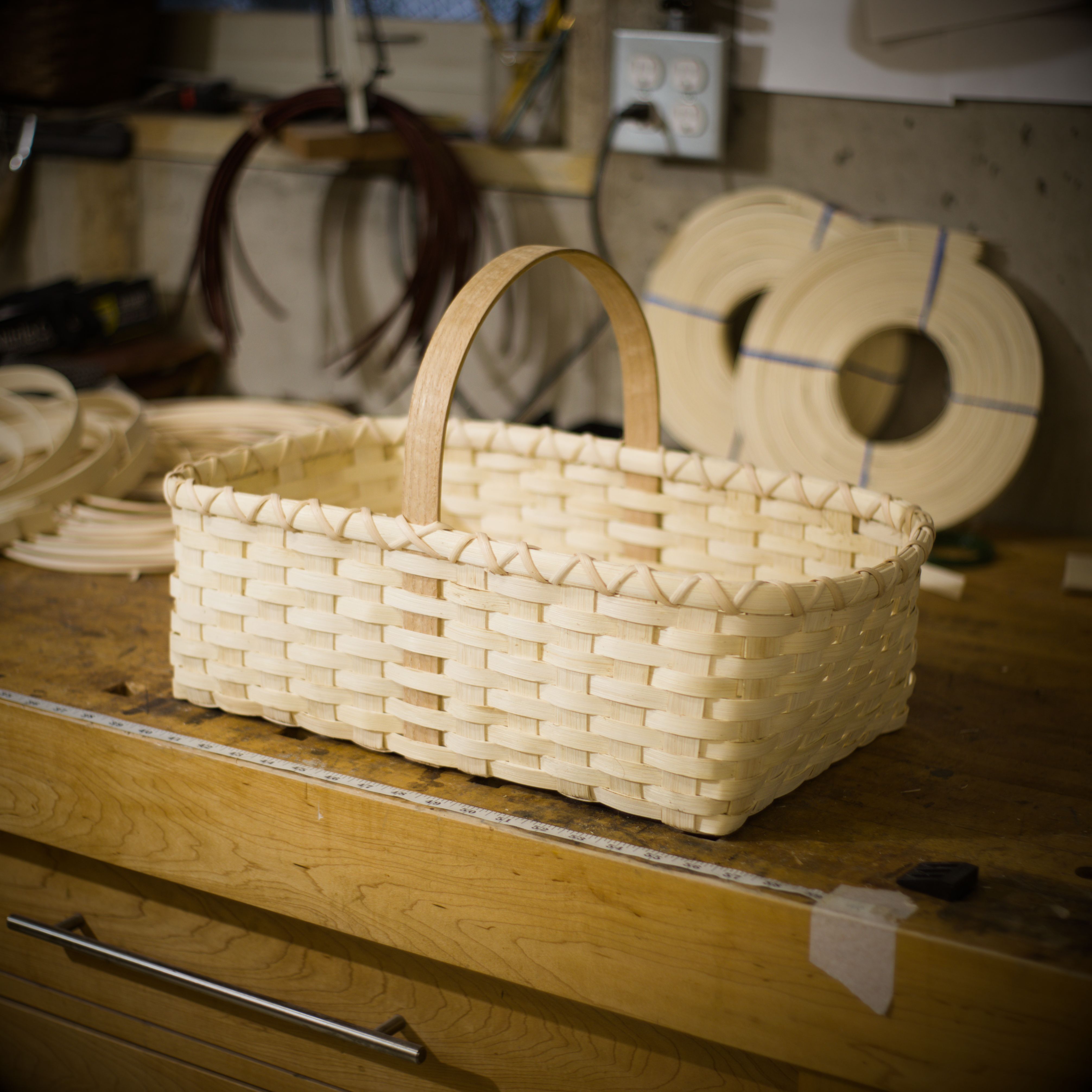 A freshly-woven natural-reed market basket on the studio bench