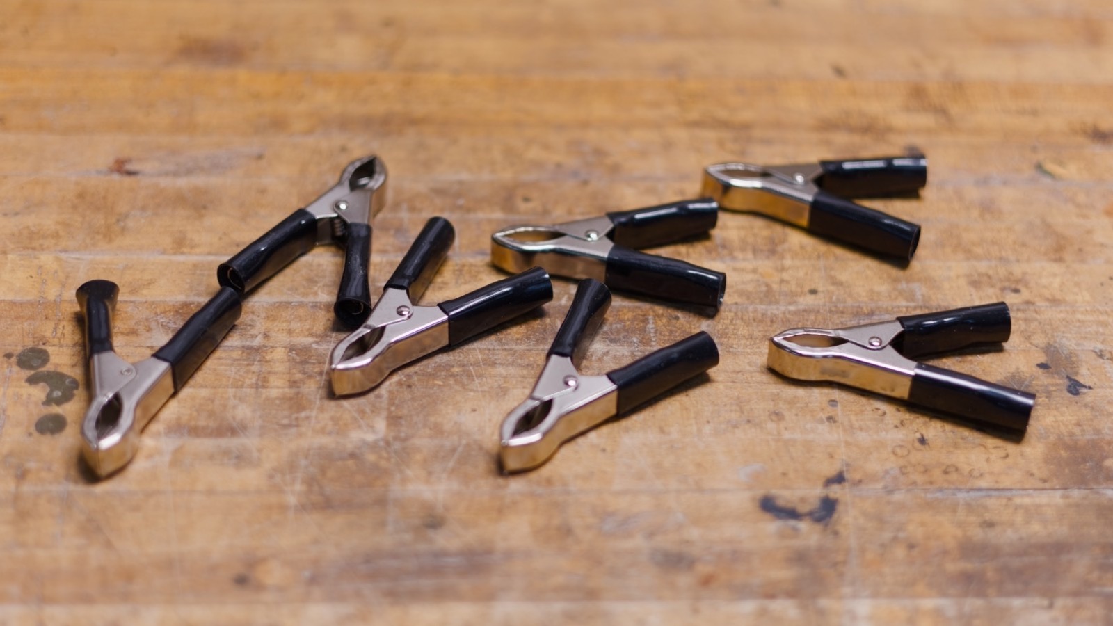 Metal hippo clips with black grips, scattered on a workbench