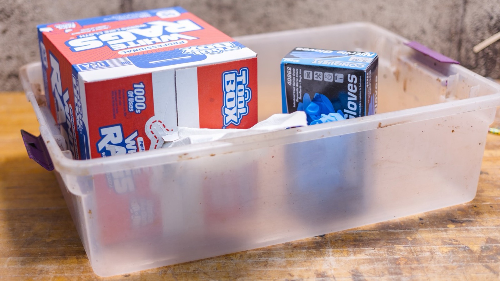 A plastic tub holding a box of rags and a box of disposable gloves
